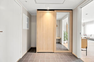 Lys og trivelig gang med moderne gulvfliser samt praktisk garderobe med eikefronter og speilglass. 